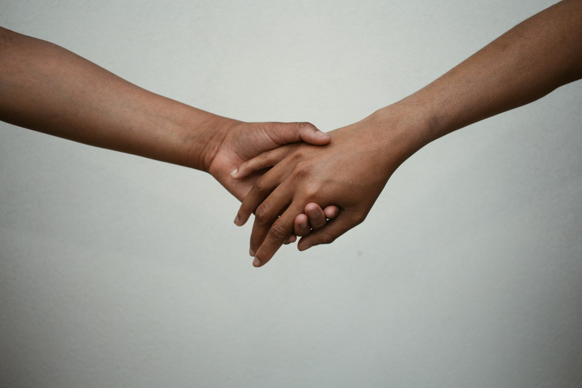 Two hands gently holding each other, a reminder that boundaries can be set with kindness